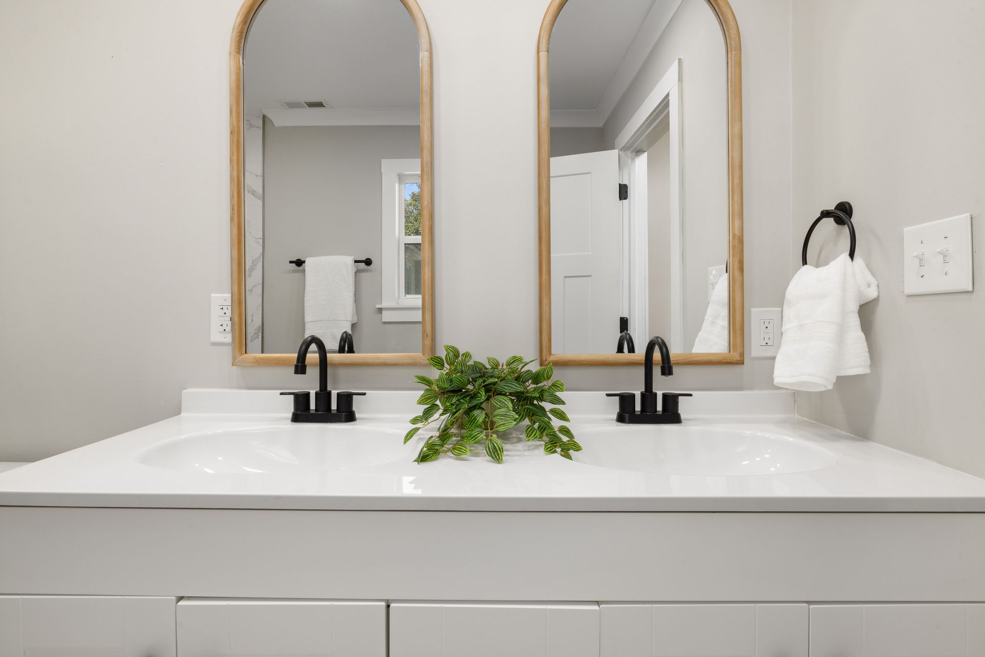 Modern bathroom vanity featuring double sinks, mirrors, and stylish black faucets.